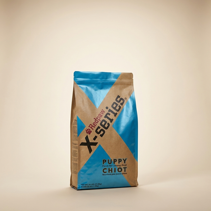 RedPaw X-Series Puppy dog food bag on warm beige studio background, satin sheen